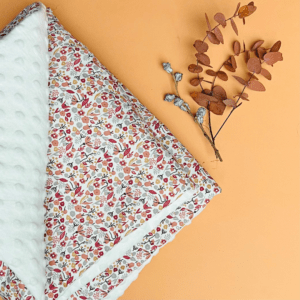 couverture molletonnée et pliée. Tissu avec des petites fleurs dans les tons marsala sur fond blanc