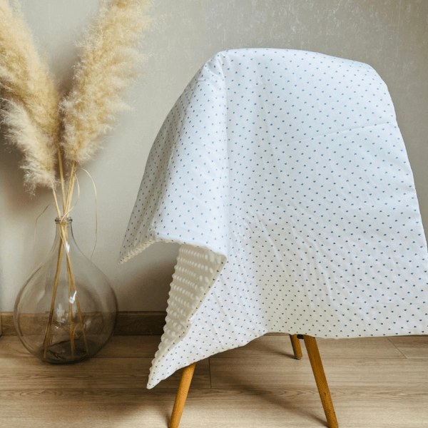 Couverture molletonnée et posée sur une chaise. Tissu petits coeurs bleus sur fond blanc