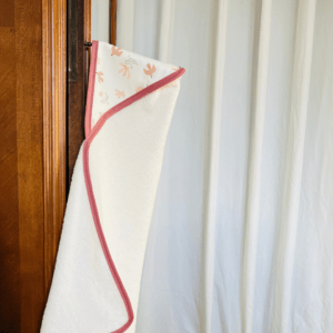 cape de bain en éponge blanche avec une capuche ayant un tissu avec des hirondelles roses sur un fond blanc